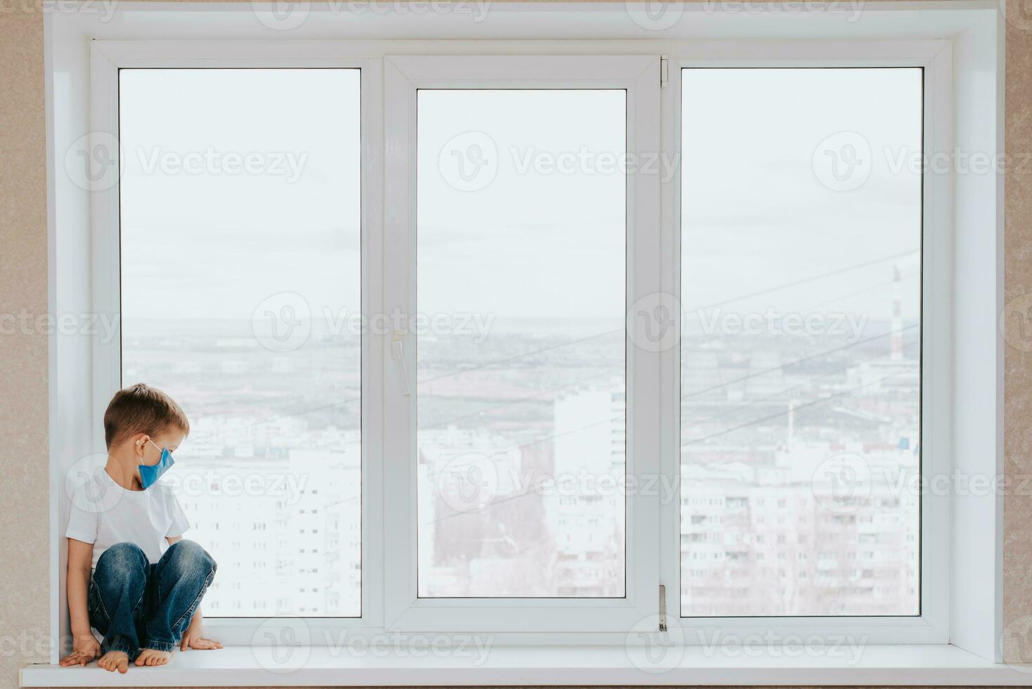 uma criança dentro uma médico mascarar é sentado às casa dentro quarentena Porque do coronavírus e cobiçado -19 e parece Fora a janela. foto