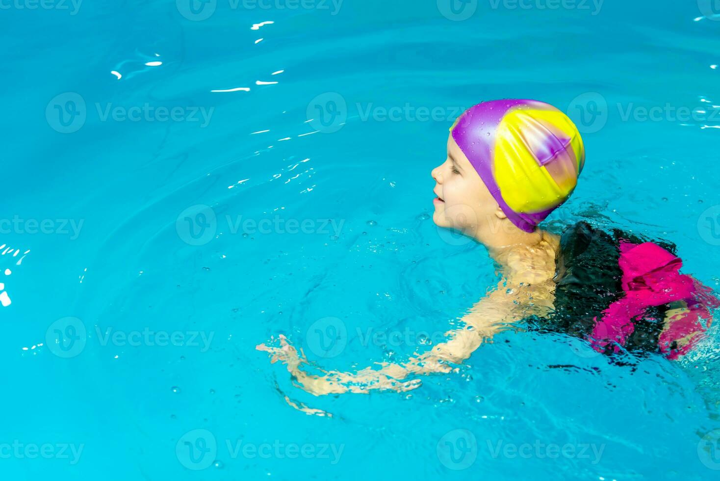 uma pequeno Garoto com uma vida Jaqueta em dele peito aprende para nadar dentro a interior piscina. foto