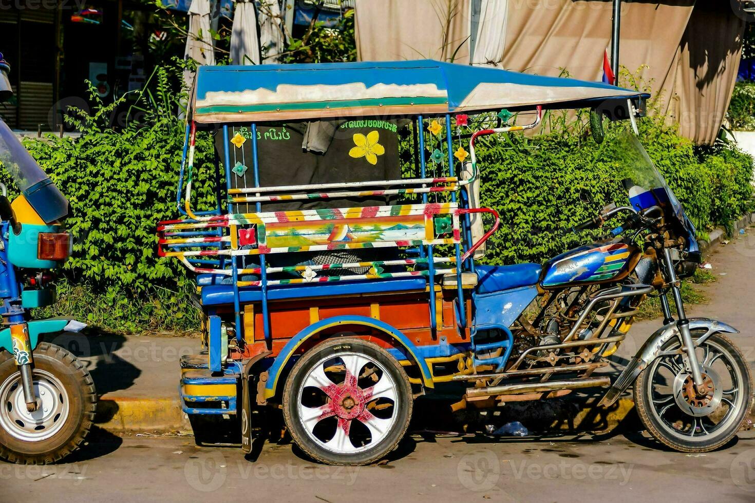 uma colorida tuk tuk estacionado em a lado do a estrada foto