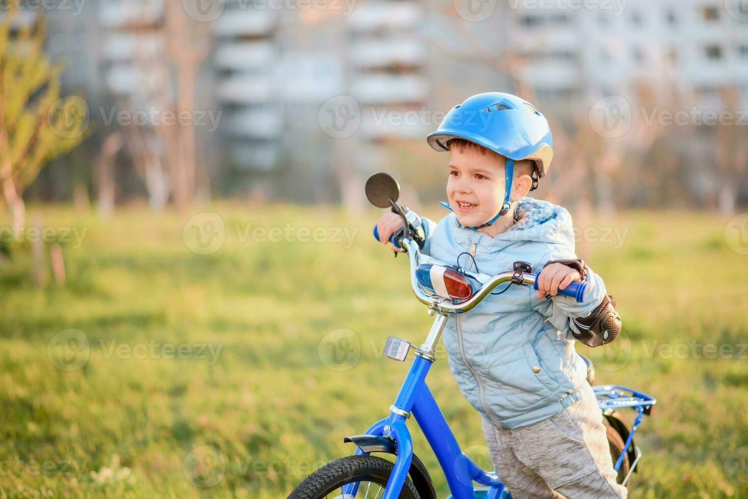 fofa criança é dirigindo uma bicicleta em uma ensolarado dia às pôr do sol foto