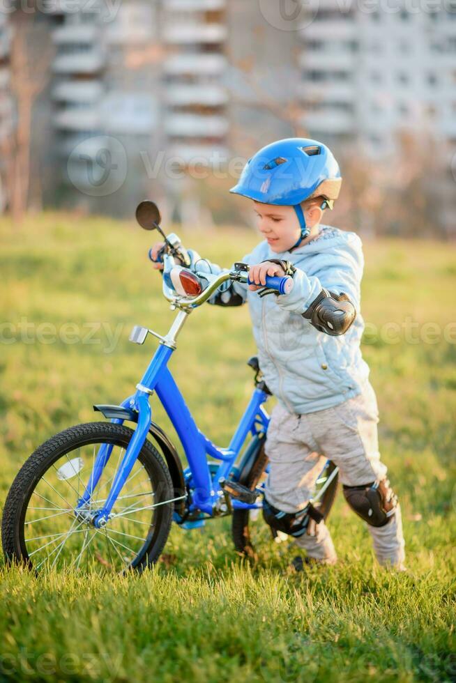 fofa criança é dirigindo uma bicicleta em uma ensolarado dia às pôr do sol foto