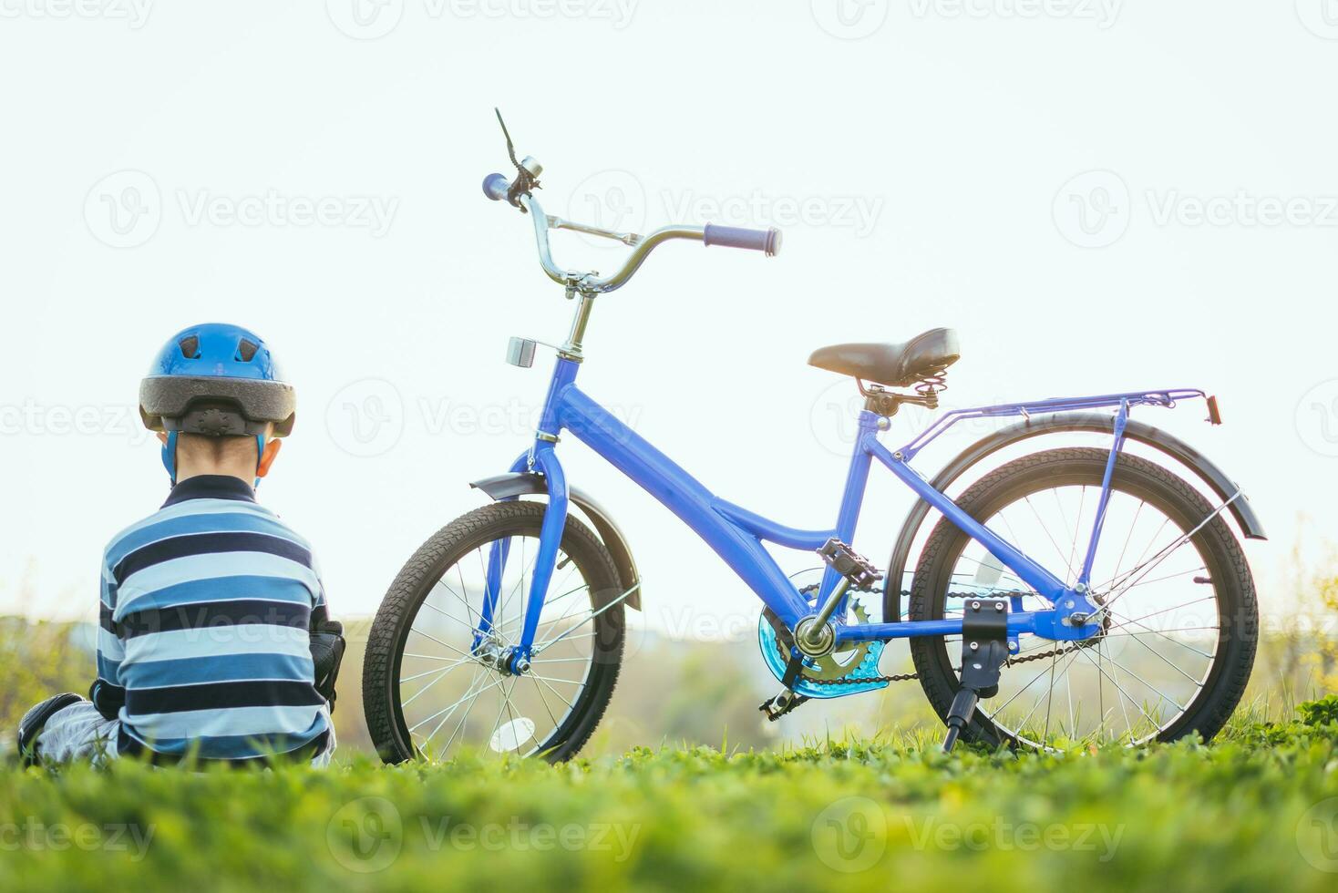 fofa criança dentro capacete e proteção senta perto dele bicicleta foto