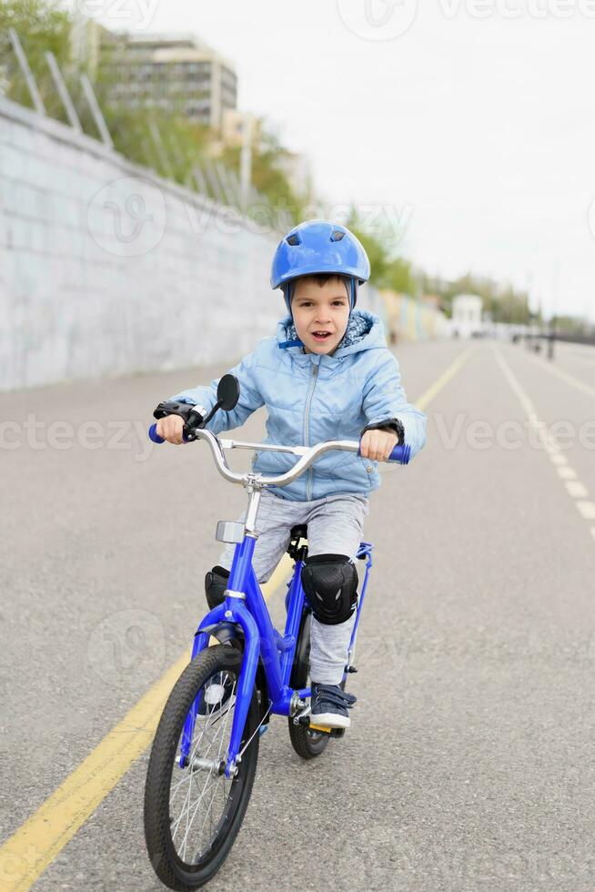 uma criança dentro uma capacete e proteção dentro uma bicicleta passeio em natureza dentro a Primavera foto