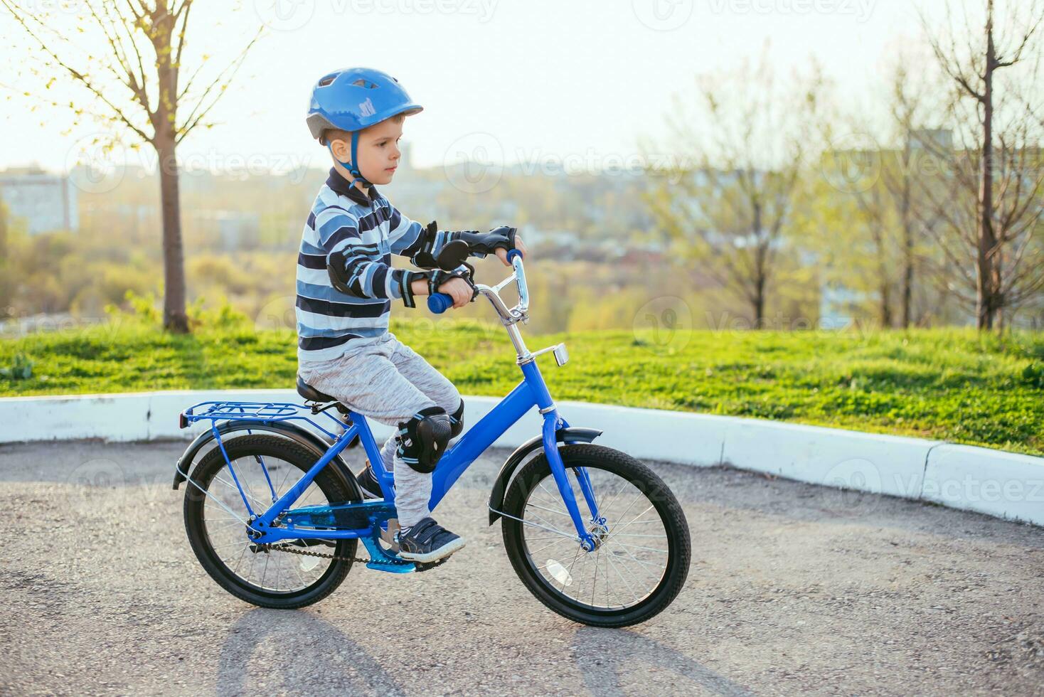 uma criança dentro uma capacete e proteção dentro uma bicicleta passeio em natureza dentro a Primavera foto