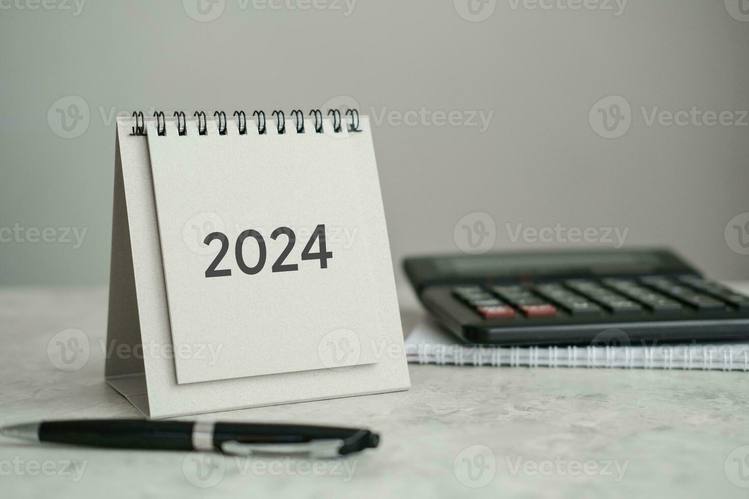 escrivaninha calendário 2024, calculadora e caneta em a mesa foto