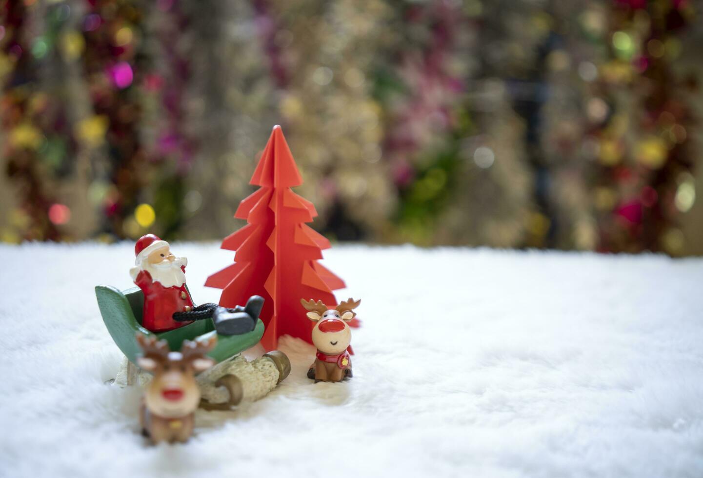 sata sentado em branco neve com grupo do presentes dentro frente do vermelho origami Natal árvore esperando para engraçado festival, Natal e Novo ano conceito. foto