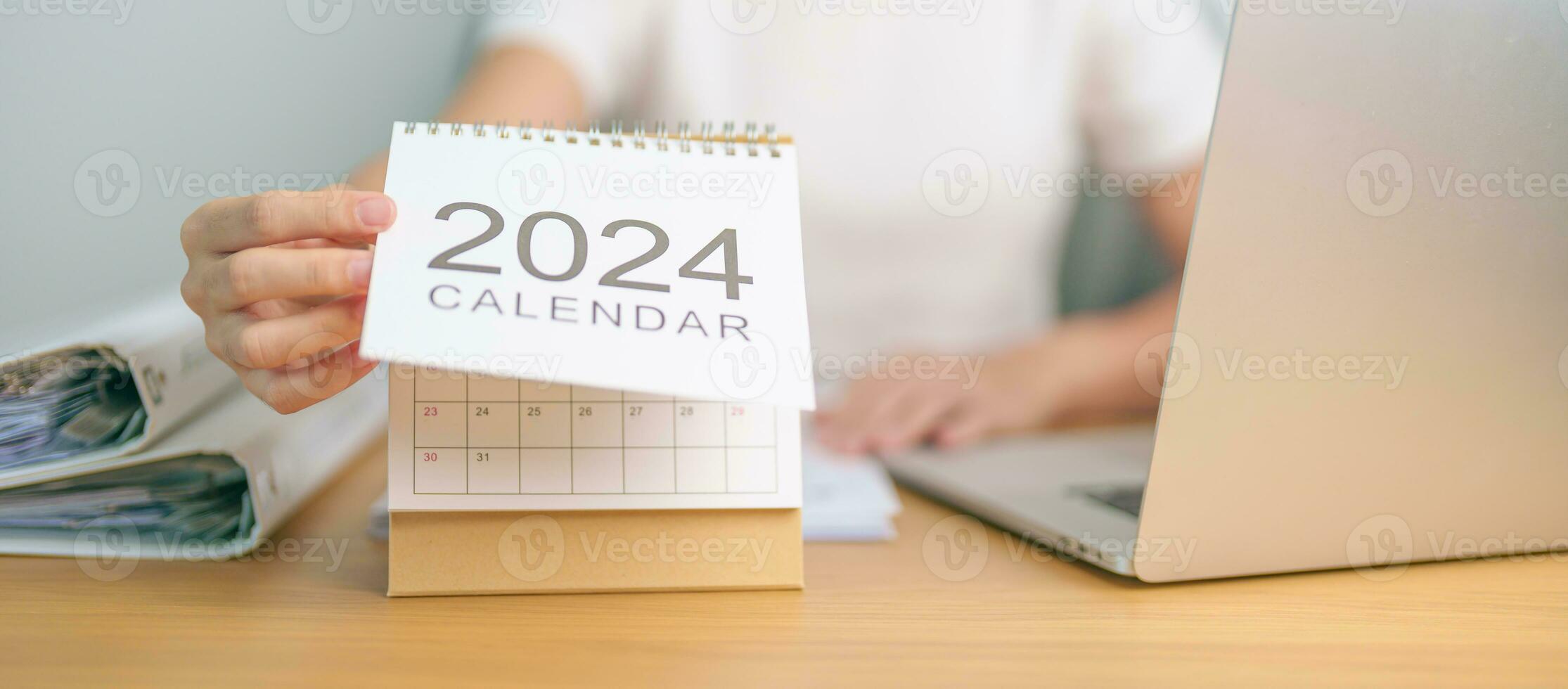 2024 ano calendário em mesa com o negócio mulher usando computador portátil computador. contagem regressiva, feliz Novo ano, resolução, metas, plano, Ação, missão e financeiro conceito foto