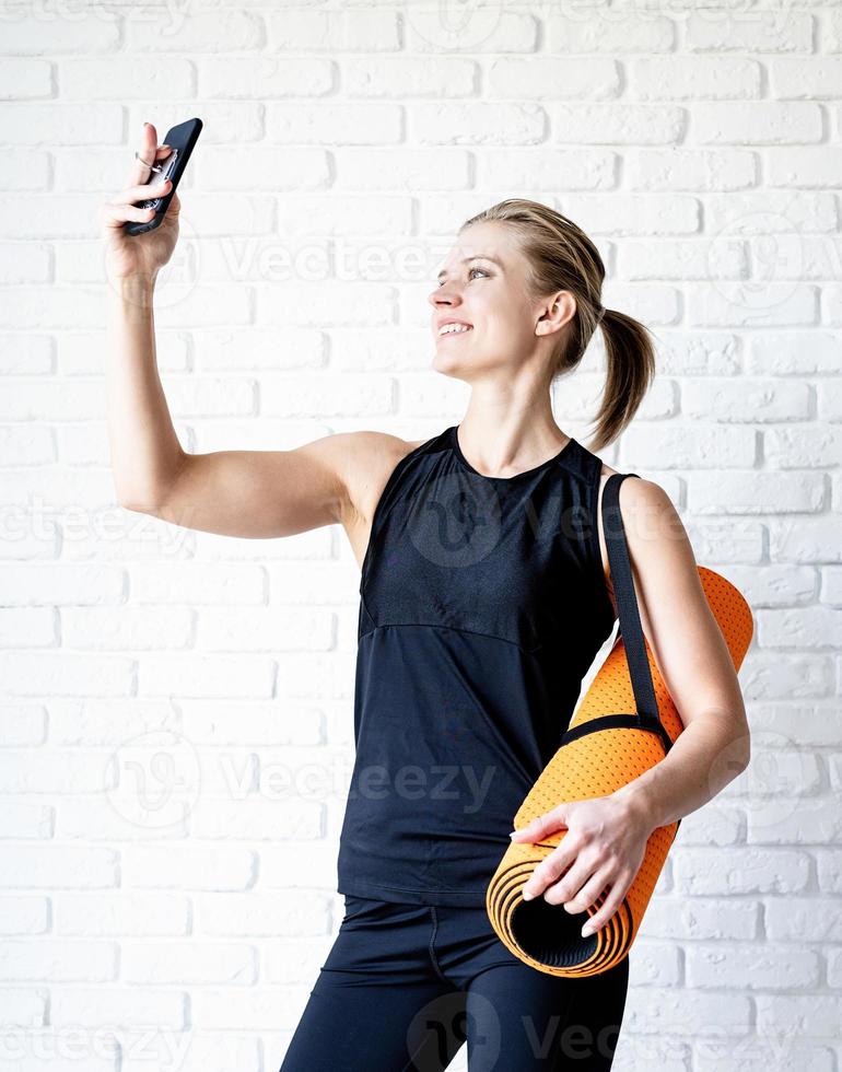 jovem sorridente fitness fazendo selfie após o treino foto