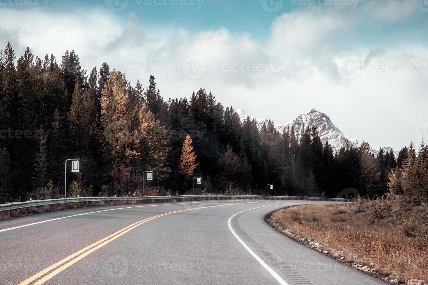 viagem de carro dirigindo em rodovia com montanhas rochosas e floresta de pinheiros no outono no parque nacional de banff foto