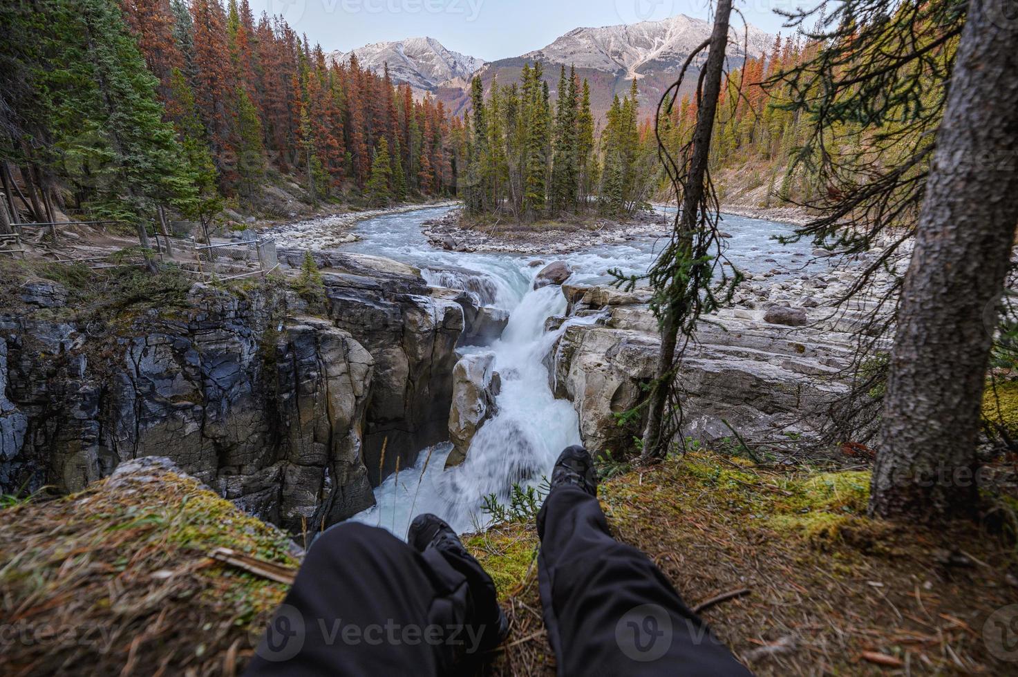 pernas viajantes sentam e se alongam nas cataratas sunwapta em campos de gelo no parque nacional de Jasper foto