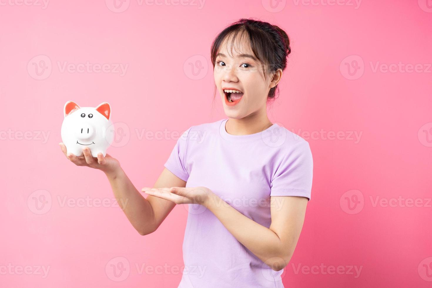 retrato de menina segurando o cofrinho na mão, isolado no fundo rosa foto