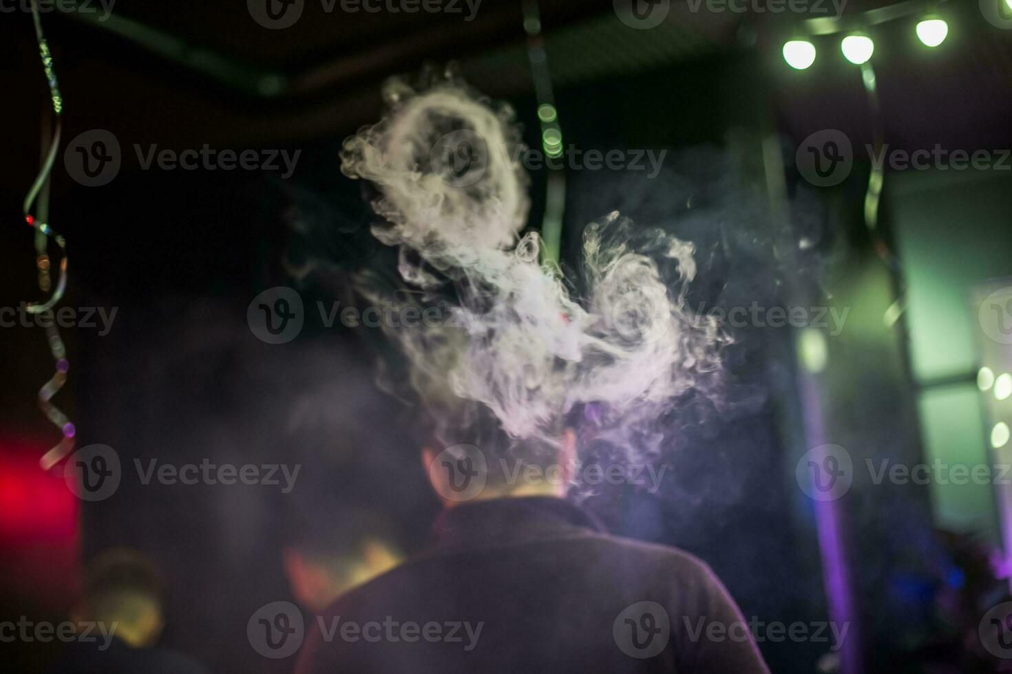 círculo do fumaça a partir de eletrônico cigarros. casais a partir de vapor. fumaça a partir de a boca do uma fumar cara. homens Cigarro eletrônico e vamos Fora círculos do fumaça. foto