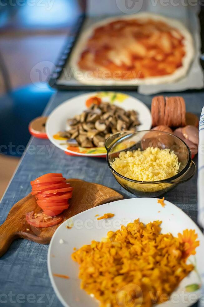 Ignegradentes para caseiro pizza. cenouras, cogumelos, Grato queijo e tomates dentro pratos em mesa. estilo de vida. feito em casa Comida durante coronavírus epidemia. foto