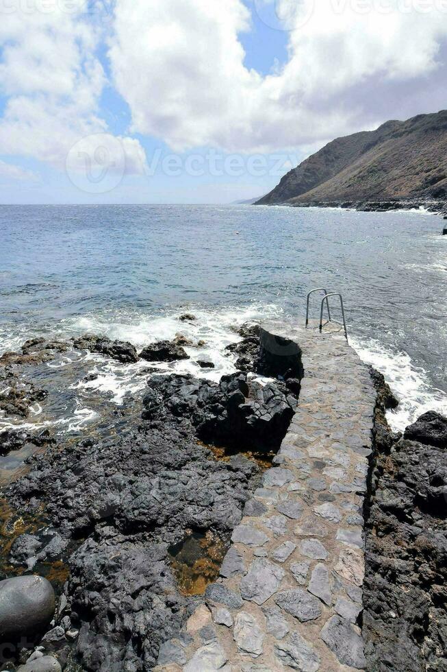 uma pedra caminho conduz para a oceano foto