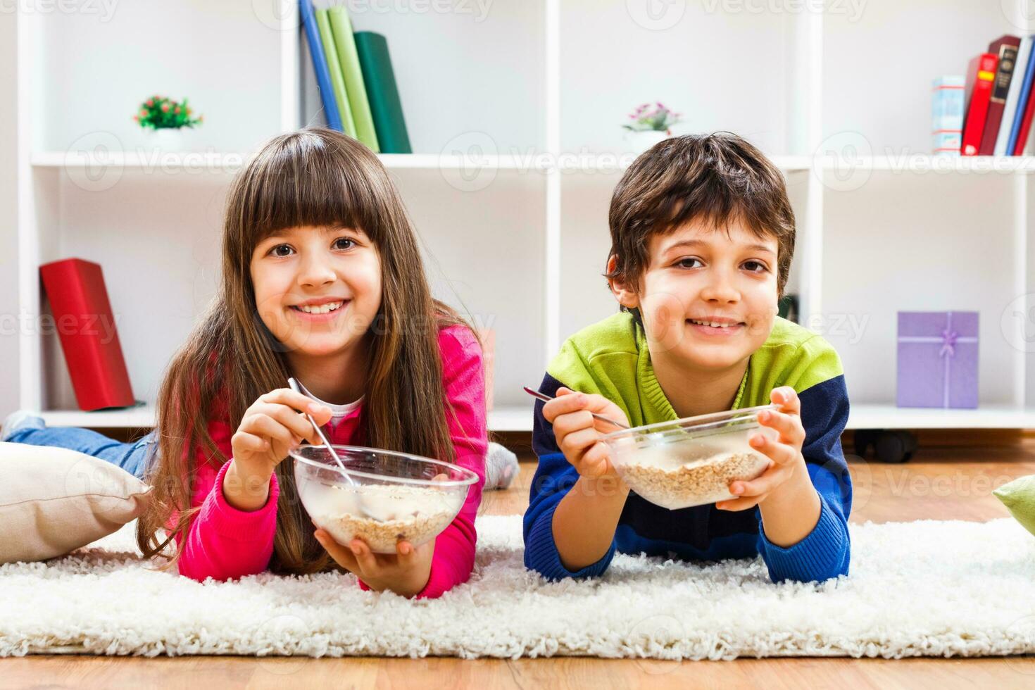 dois crianças comendo cereal em a chão foto