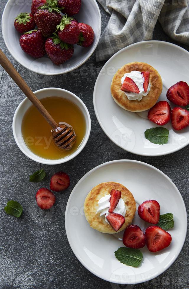 panquecas de queijo cottage, bolinhos de ricota na placa de cerâmica com morango fresco. foto