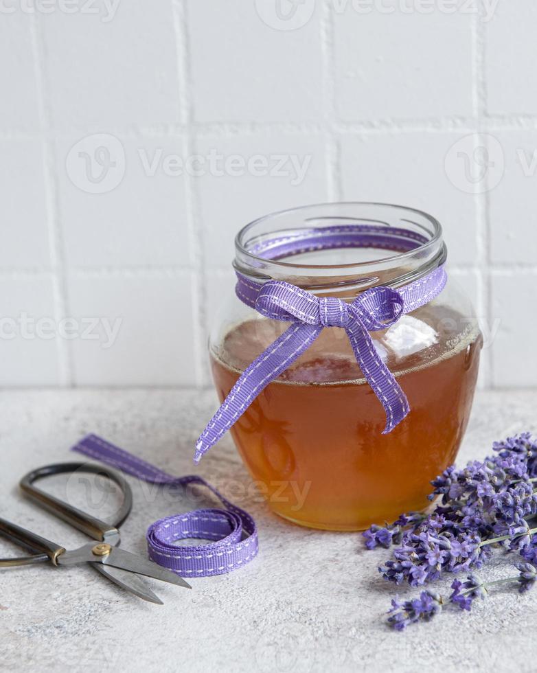 jarra com mel e flores frescas de lavanda foto