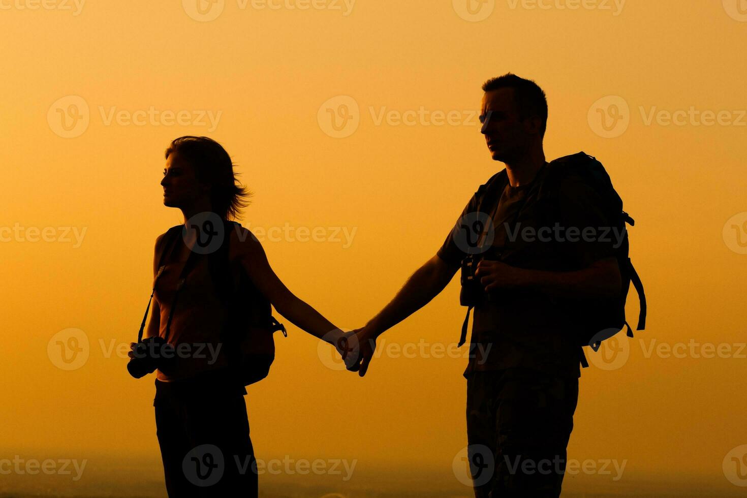 casal com mochila assistindo a pôr do sol foto