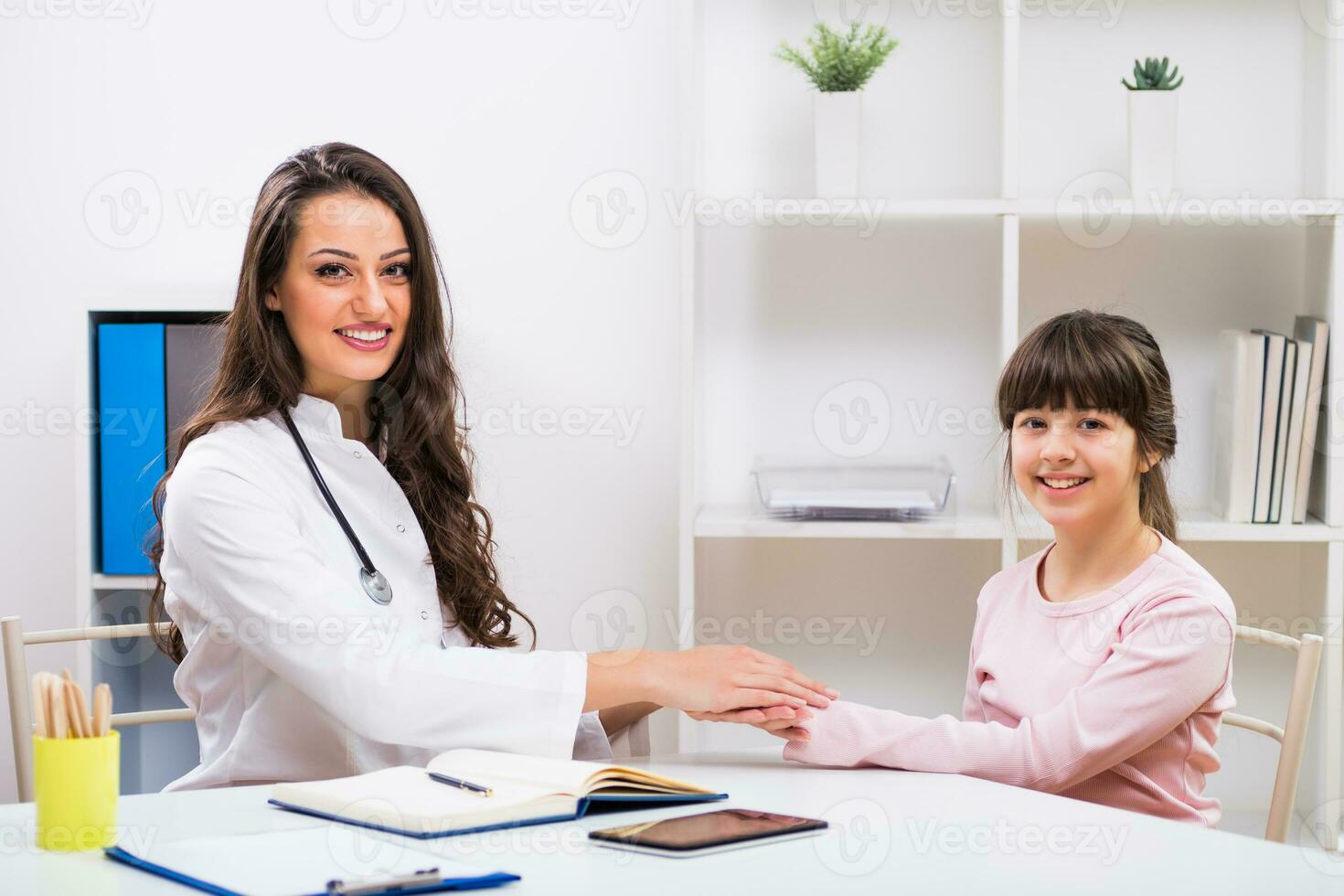 fêmea médico e criança segurando mãos às a médico escritório foto