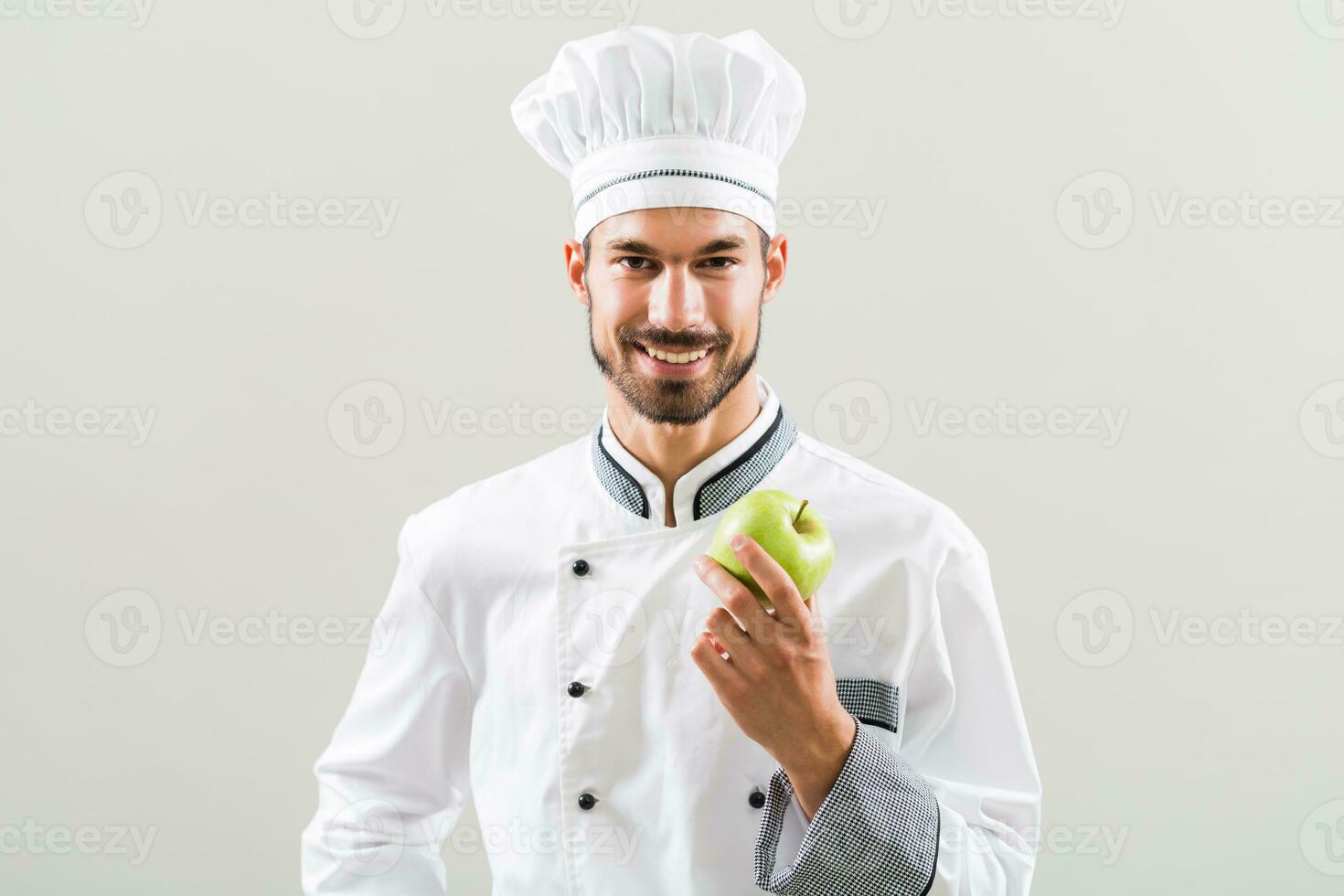chefe de cozinha é segurando maçã e laranja em cinzento fundo. foto