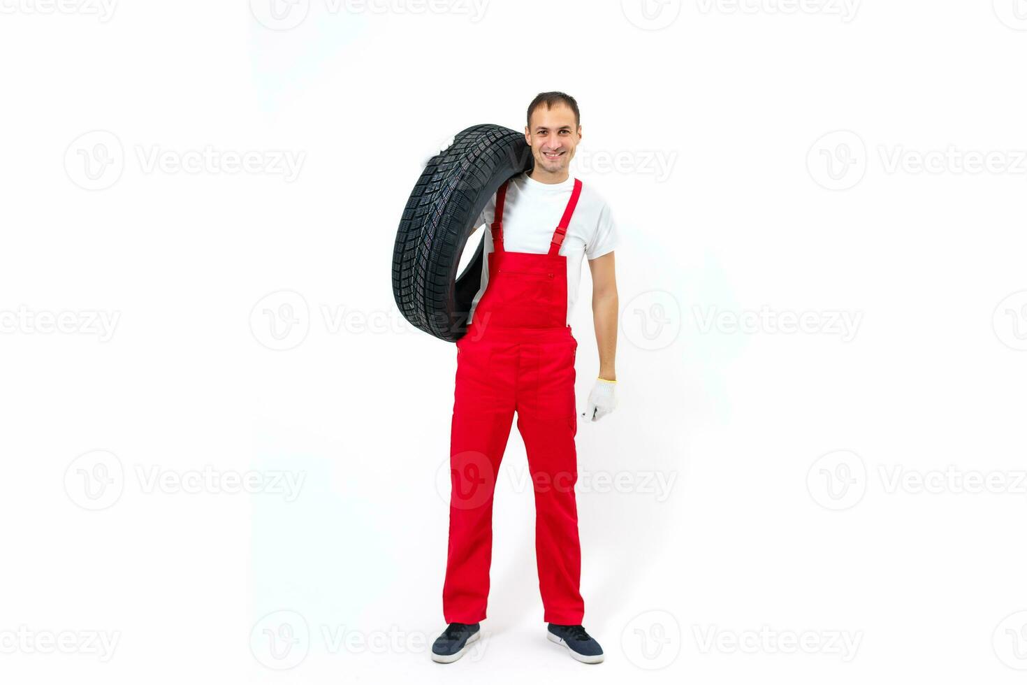 retrato do sorridente masculino mecânico segurando pneu em branco fundo foto