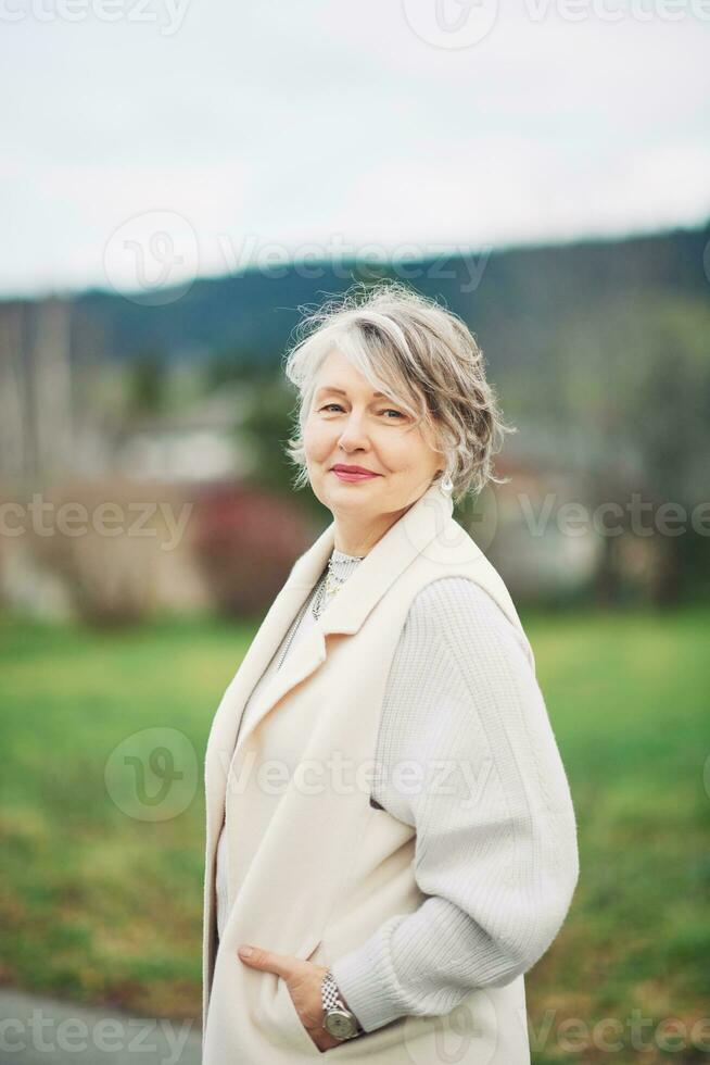 ao ar livre retrato do lindo meio era mulher, vestindo branco casaco foto