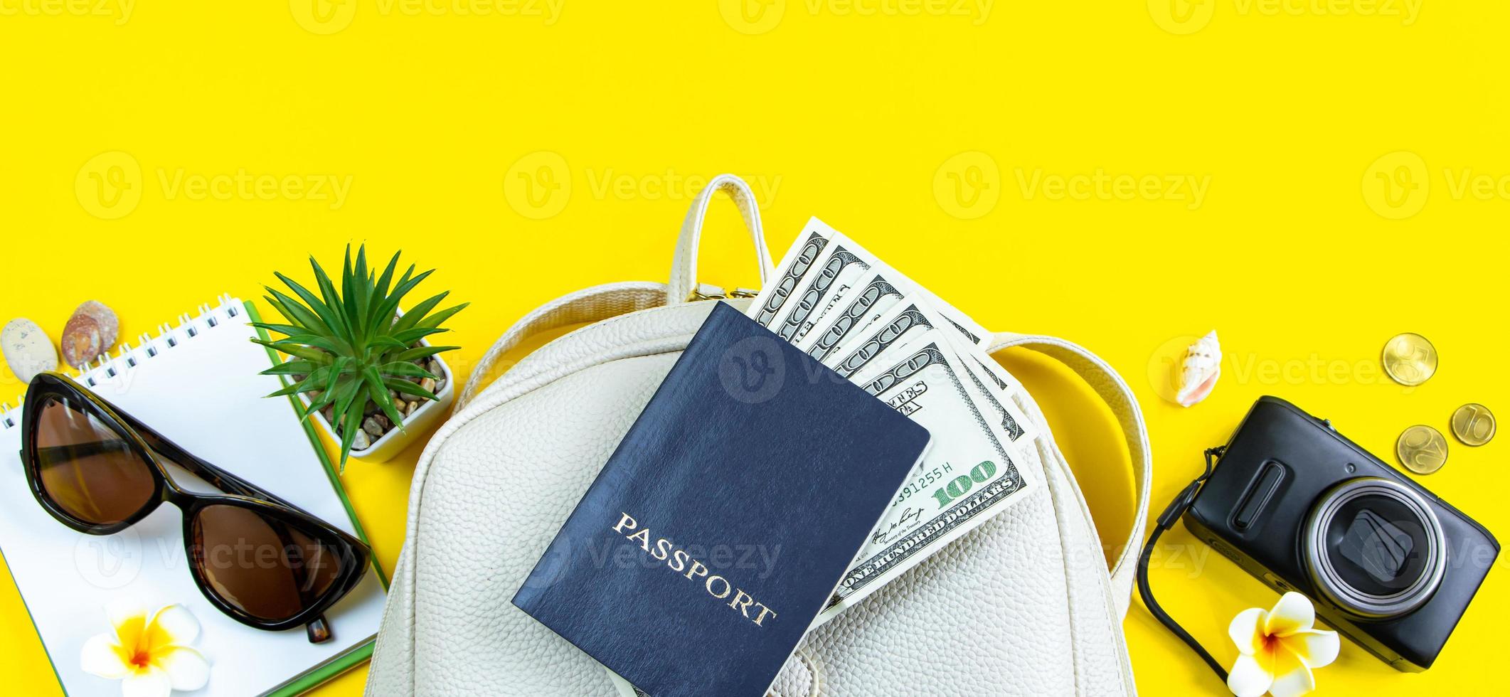 conceito de viagens de verão. passaporte, dinheiro, óculos escuros e uma câmera em um fundo amarelo. formato de banner foto