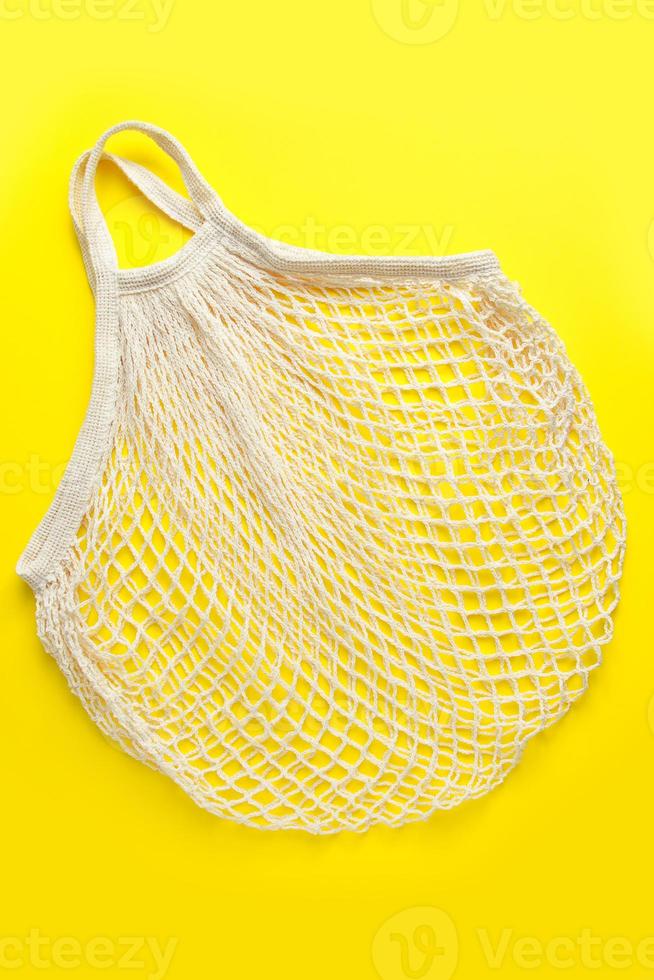 saco de malha ecológica em fundo amarelo. saco de algodão orgânico reciclável. estilo de vida sustentável e compras. foto
