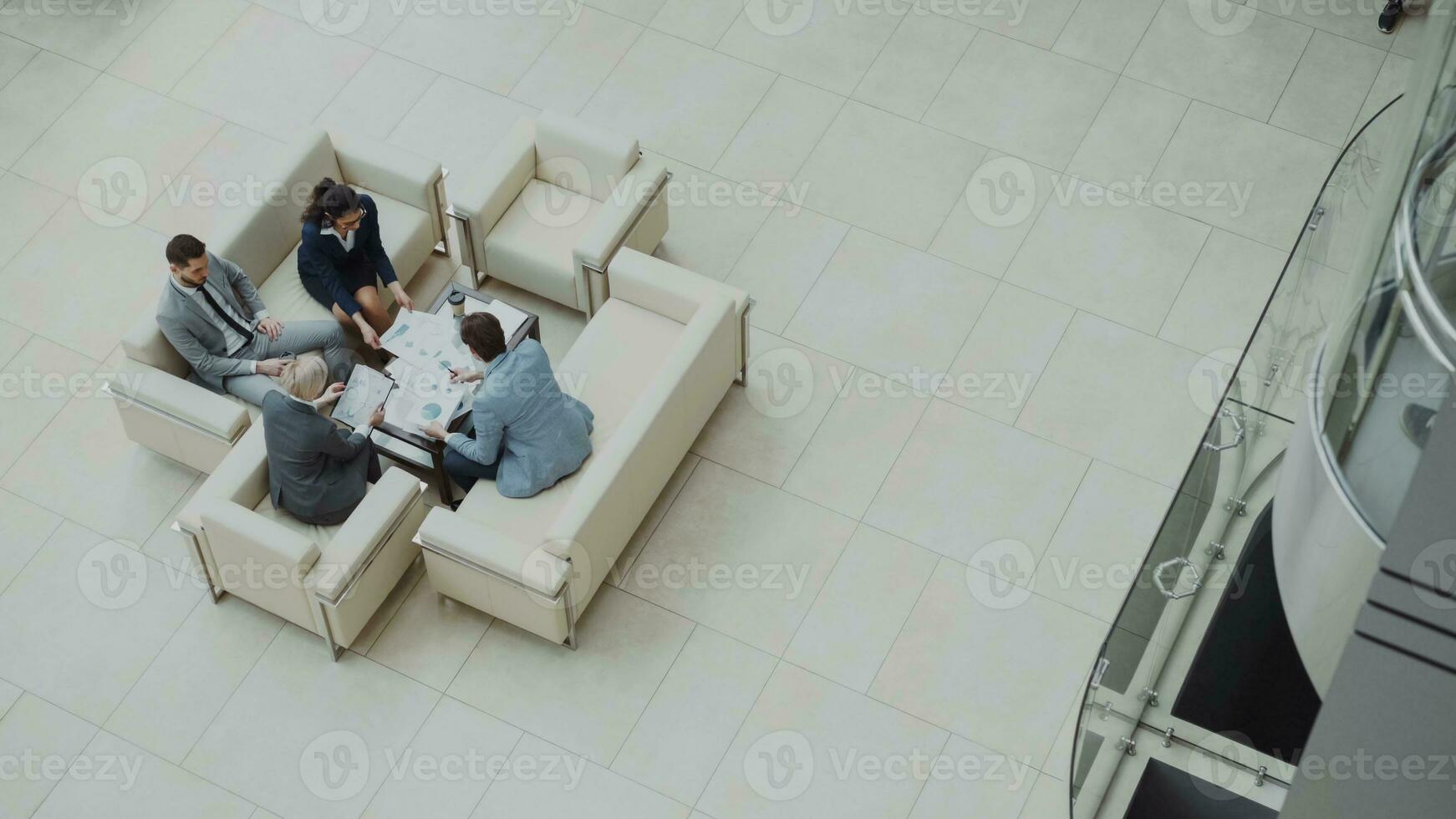 topo Visão do grupo do o negócio pessoas colegas discutindo financeiro gráficos sentado em sofás dentro lobby às moderno o negócio Centro dentro de casa foto