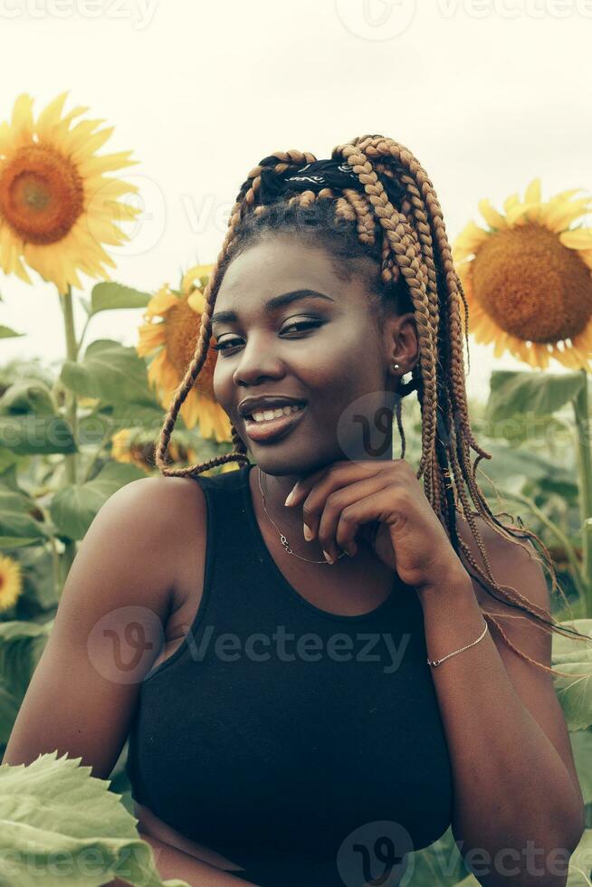 africano americano menina dentro uma campo do amarelo flores às pôr do sol foto