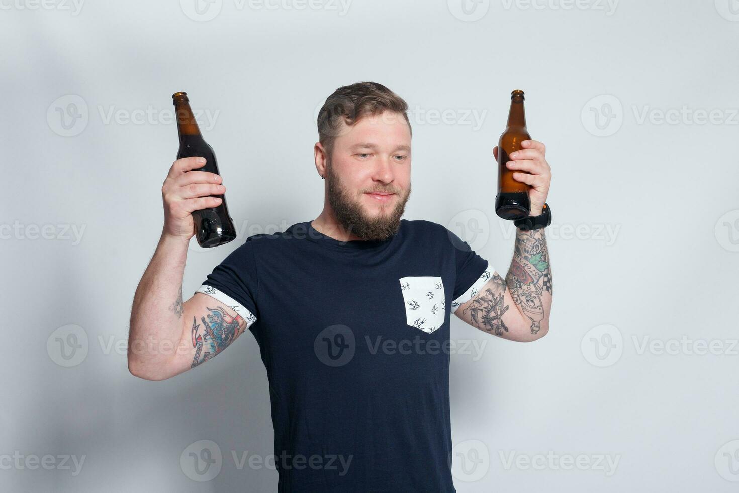 brutal barbudo masculino com tatuado braço bebidas uma Cerveja a partir de uma garrafa. foto