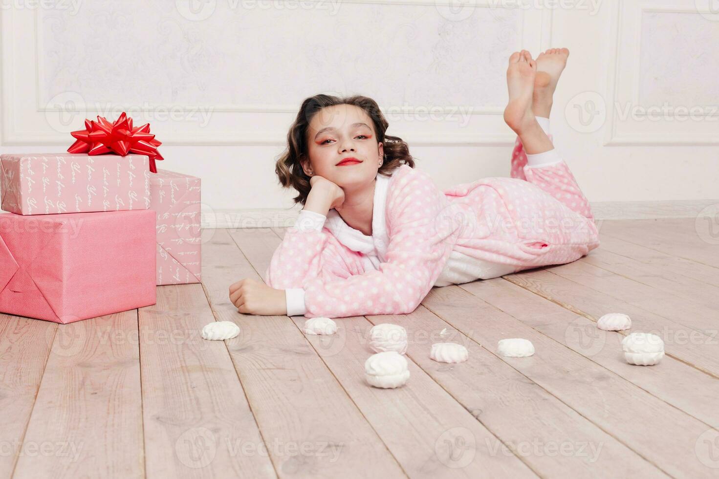 fofa pequeno menina dentro pijama com doces sentado em a chão foto