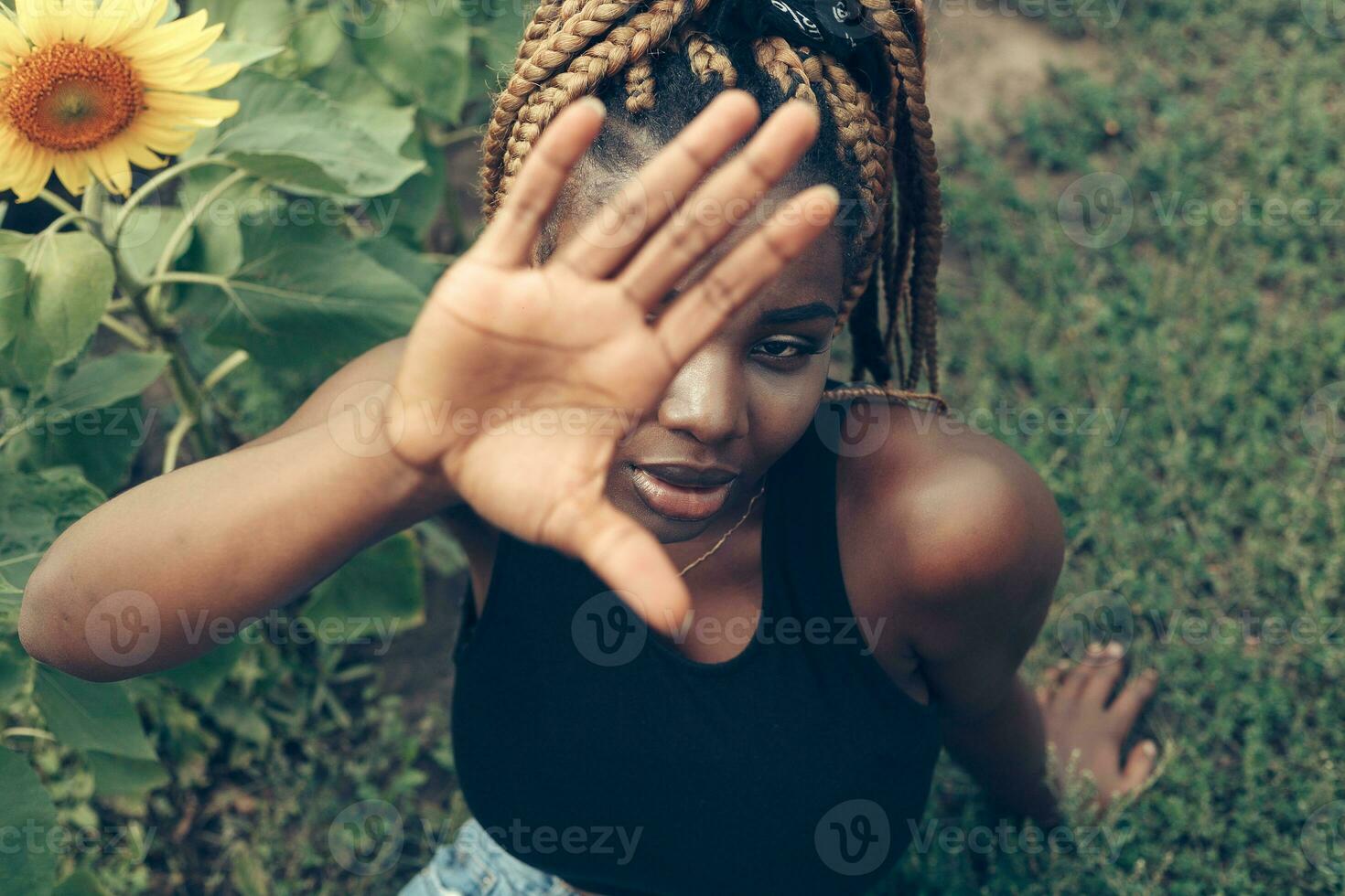 africano americano menina dentro uma campo do amarelo flores às pôr do sol foto