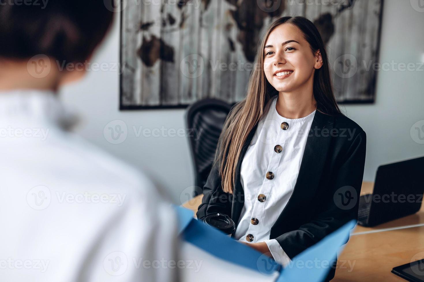 garota atraente e sorridente trabalha no escritório com o colega. foto