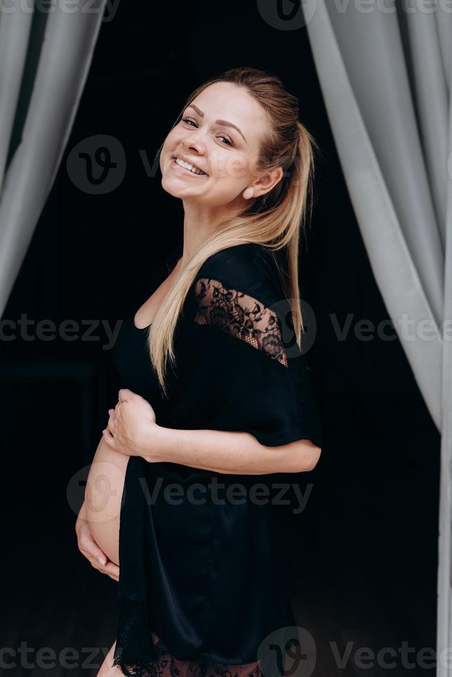 jovem grávida feliz posando com uma moeda de um centavo preto foto