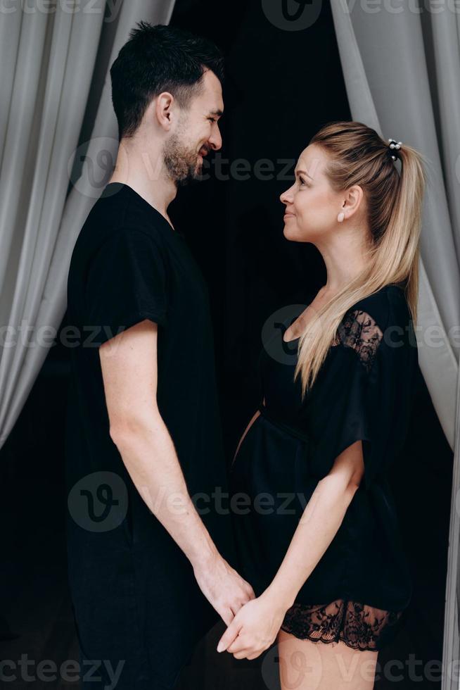 casal feliz de mãos dadas, cara a cara, esperando o bebê foto