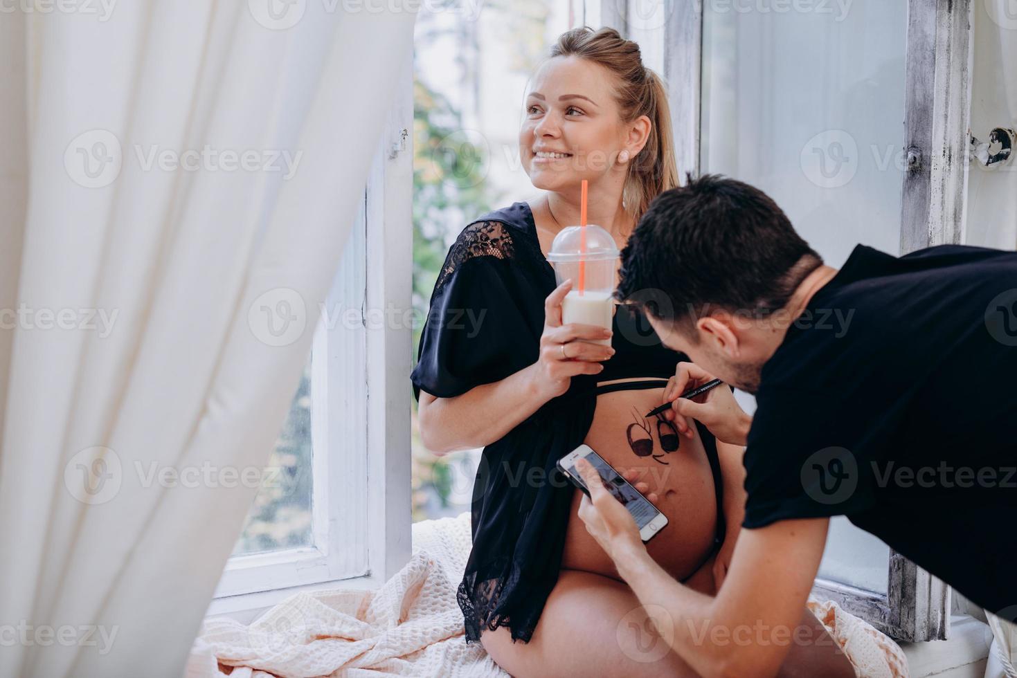 um homem pinta uma barriga de grávida, conceito de família feliz foto