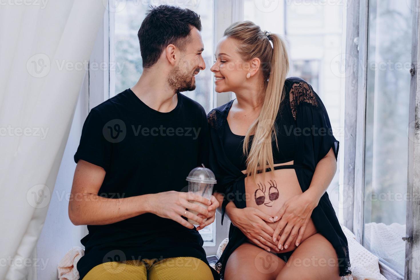 casal grávida feliz posando para a janela foto