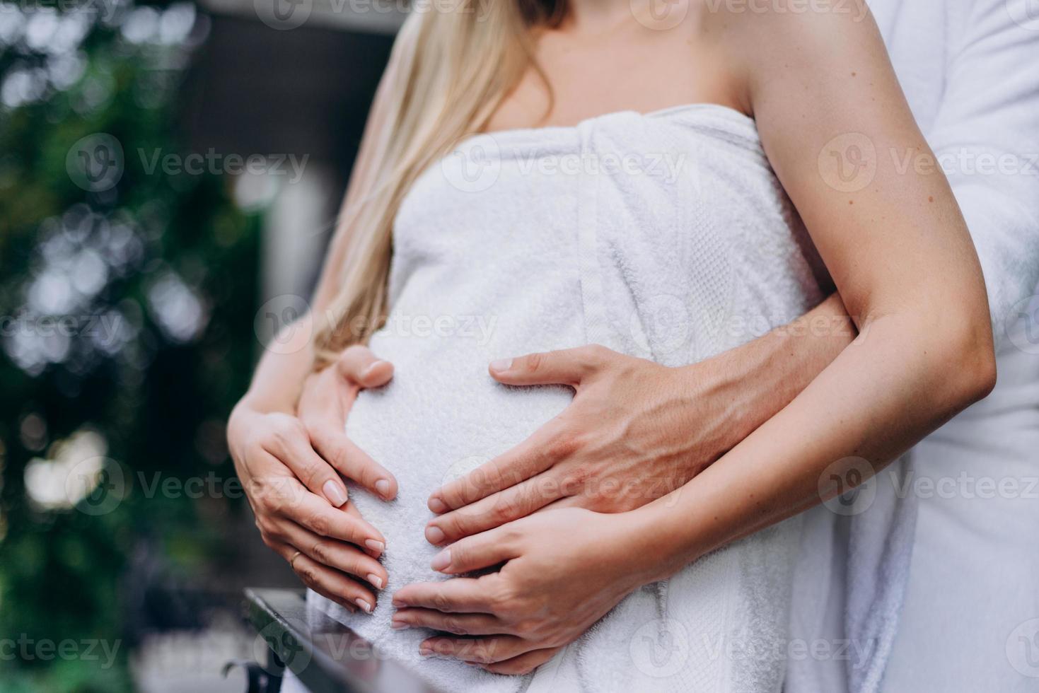 um homem abraça uma mulher grávida, feche a barriga foto