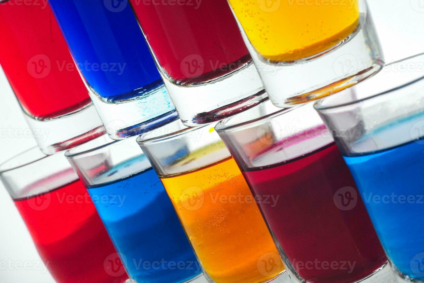 pequeno óculos preenchidas com colorida água estão ordenadamente arranjado em a isolado branco fundo foto
