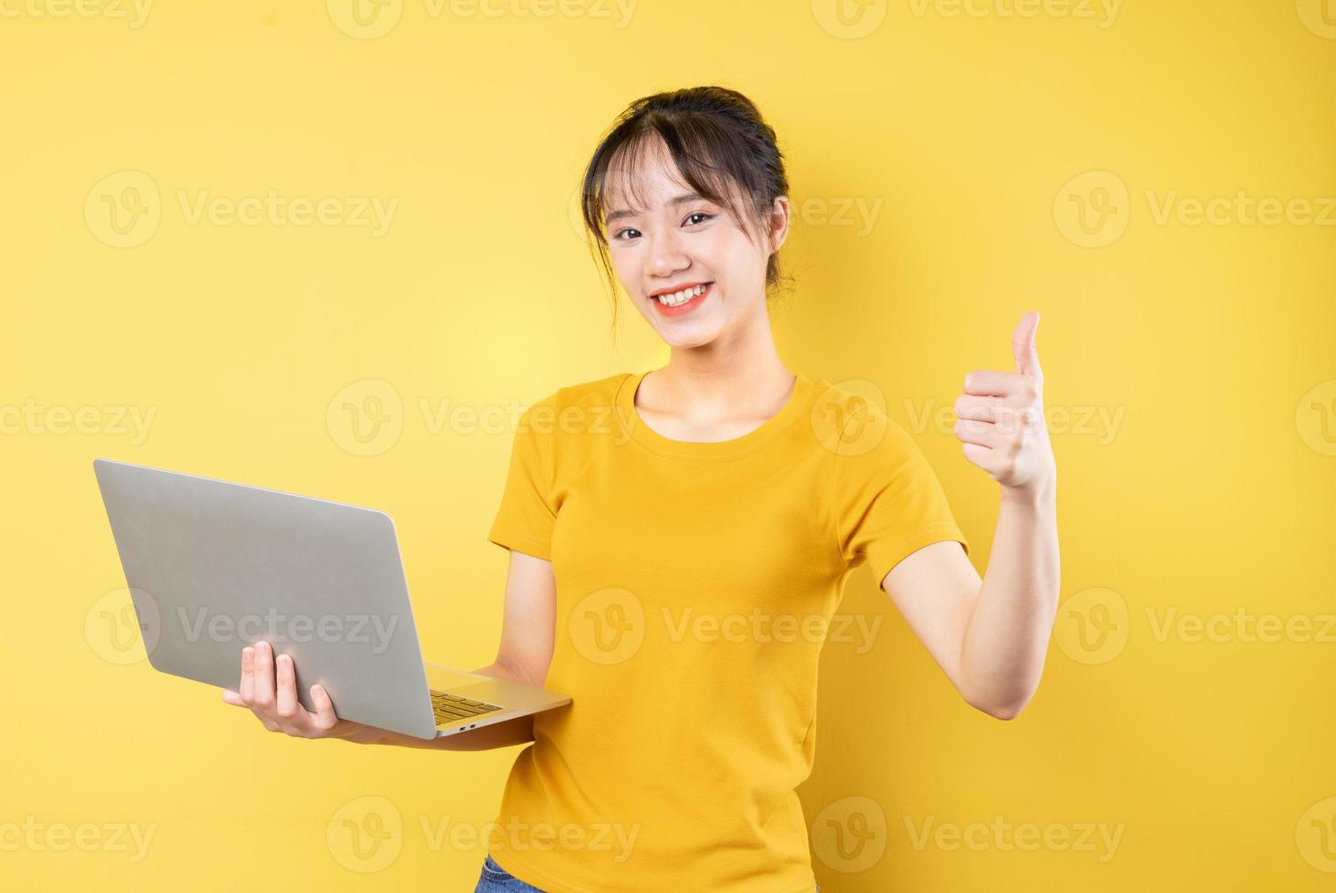 retrato de jovem segurando laptop na mão sobre fundo amarelo foto