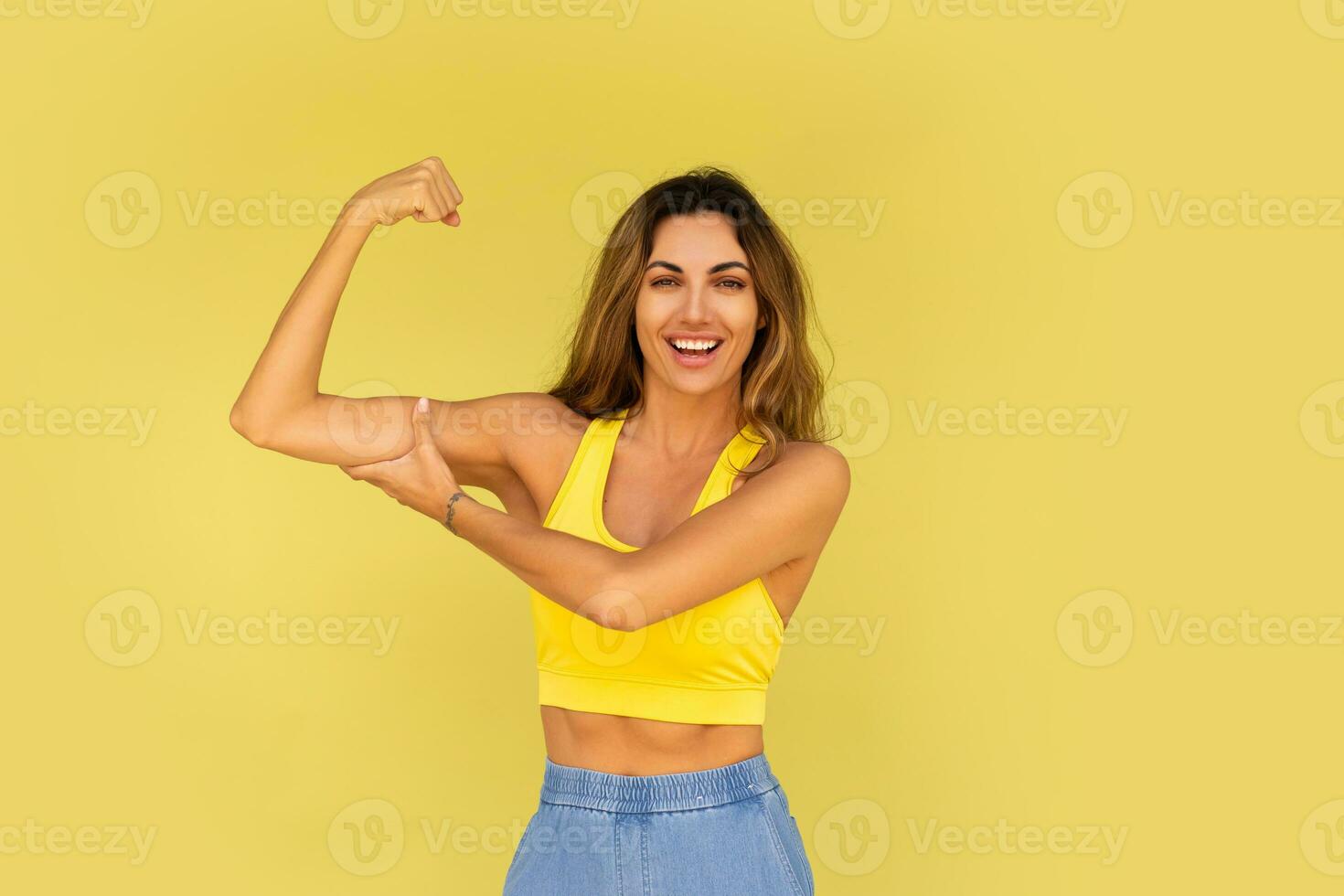 estúdio foto do bonita morena mulher dentro esportivo equipamento posando em amarelo fundo.