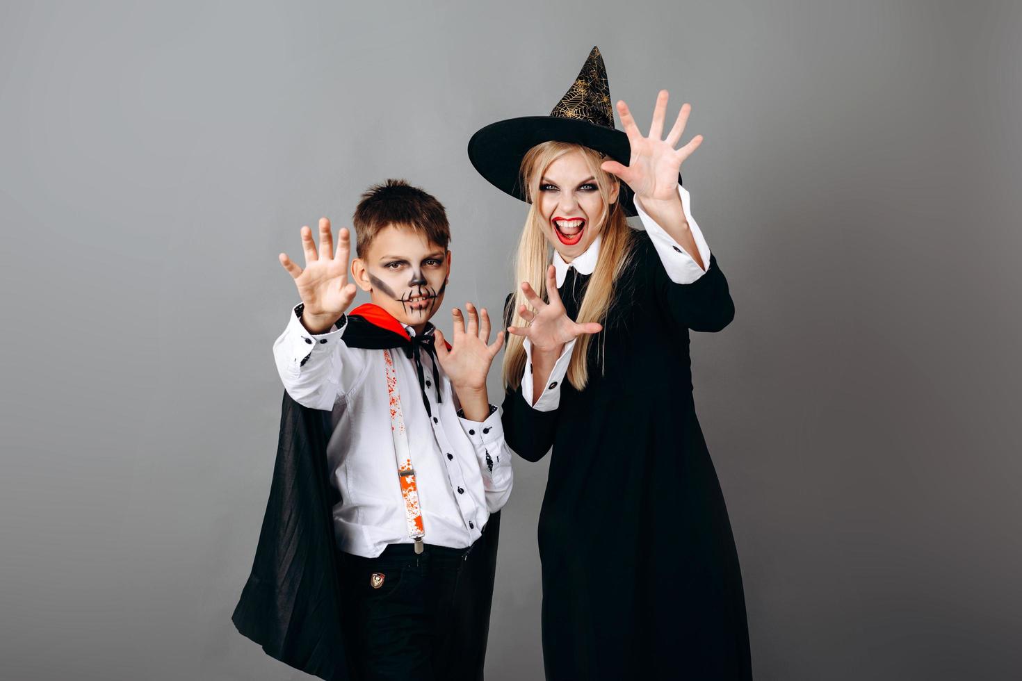 mãe e filho em fantasias mostrando um gesto assustador para a câmera. - conceito de halloween foto