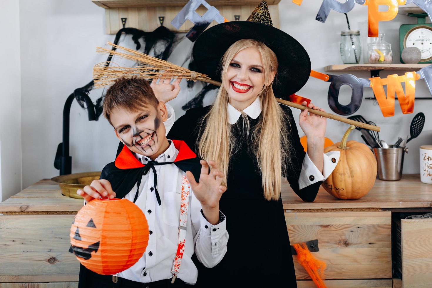 mãe e filho felizes parados em um vestido chique segurando a bomba e a vassoura foto