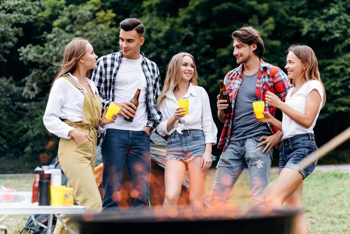 uma companhia de amigos no acampamento levantando uma garrafa de cerveja e se divertindo no acampamento foto