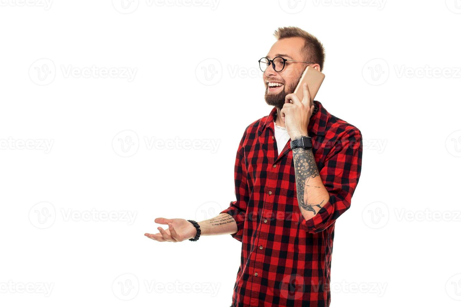 retrato do uma casual jovem homem Falando em a telefone e sorridente enquanto olhando ausente, em algum lugar acima. estúdio tiro em branco fundo foto