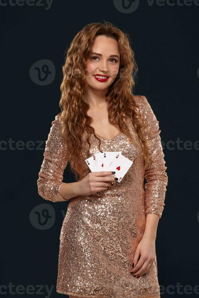 lindo jovem emocional mulher dentro coquetel vestir mostrando dela cartões para adversário, quatro do ases, melhor mão. preto fundo, estúdio tiro foto