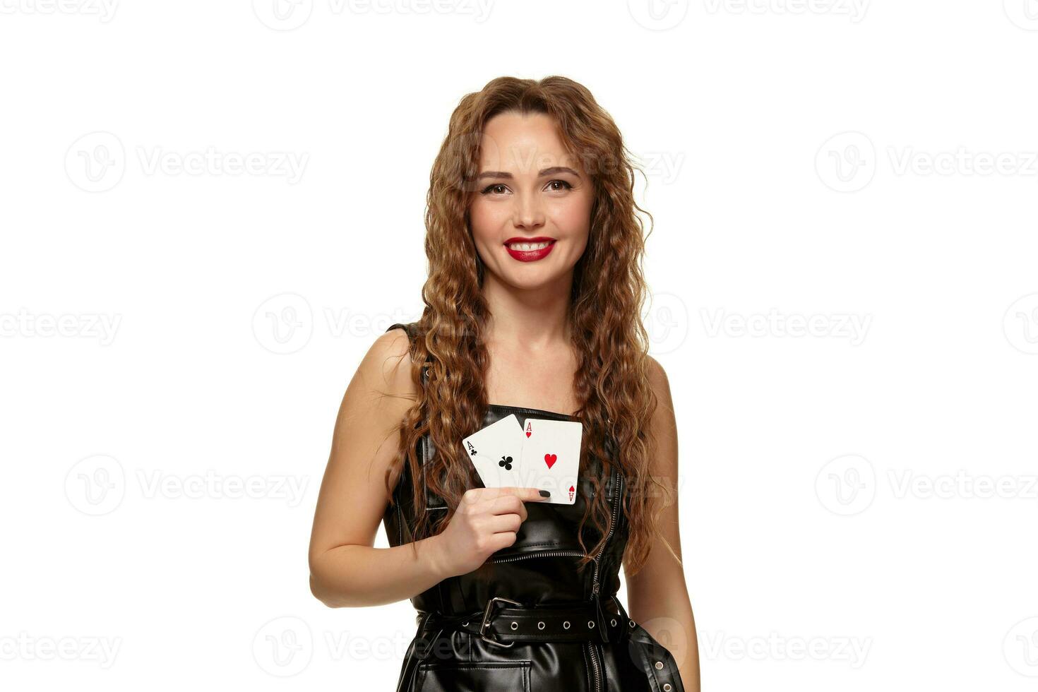 bonita jovem ruiva ou cabelos castanhos mulher segurando par do ases dentro Preto couro vestir isolado em branco foto