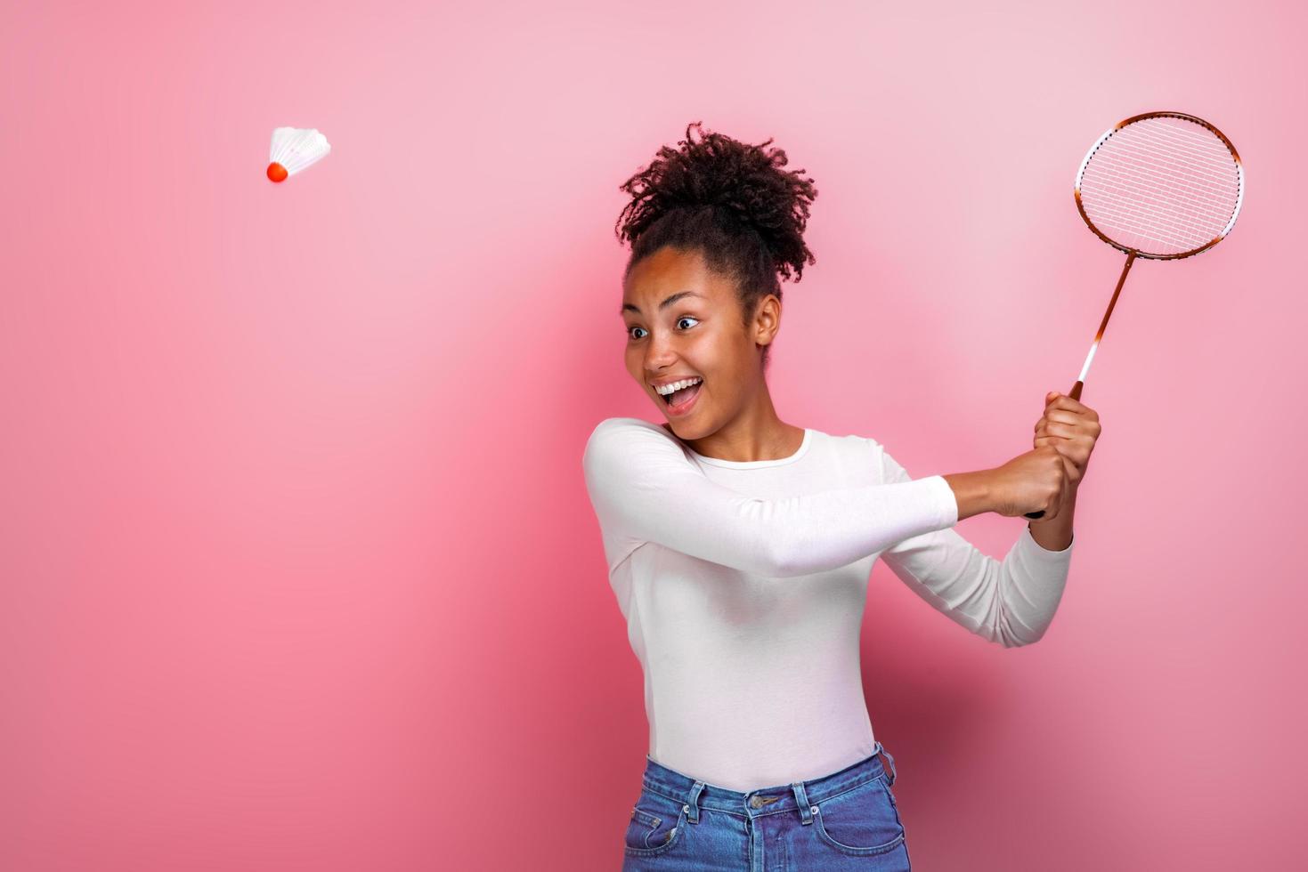 menina bonita jogando badminton no estúdio com emoção de felicidade foto