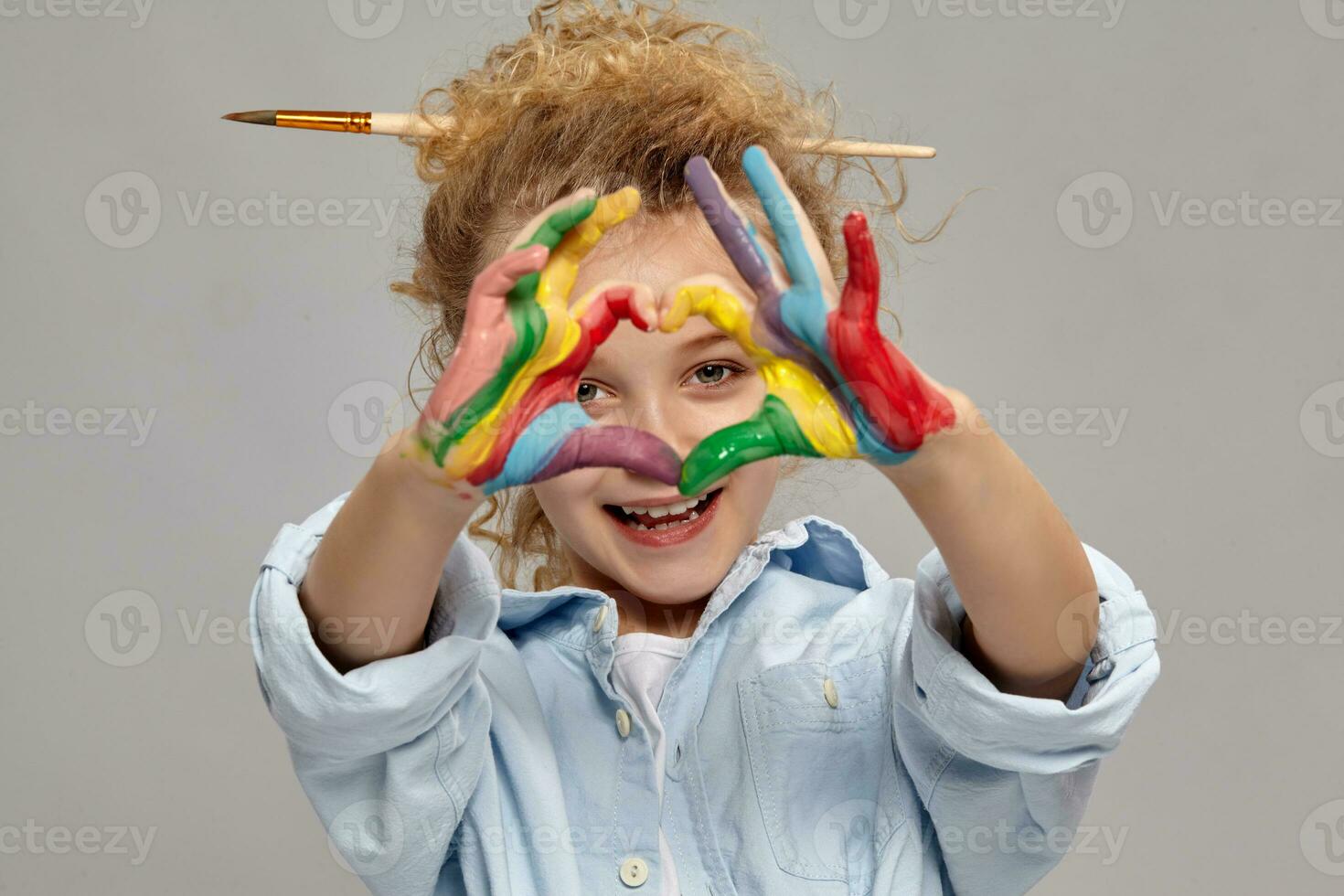 lindo pequeno menina com uma pintado dedos é posando em uma cinzento fundo. foto